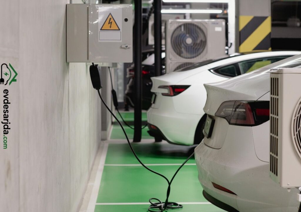 Kapalı otoparkta elektrik panosuna bağlı şarj kablosu ve elektrikli araçlar