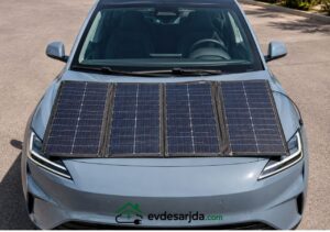 Kaputunun üzerine taşınabilir güneş paneli yerleştirilmiş modern bir elektrikli otomobilin önden görünümü.